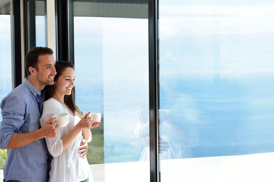 Couple with coffee mugs enjoying scenic views out the large windows at Seascape at Weymouth